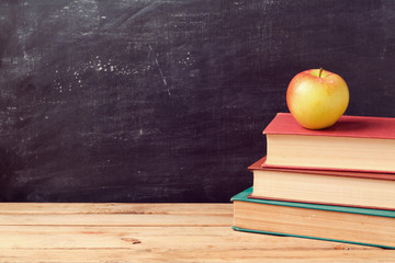 Obraz premium Back to school background with books and apple over chalkboard