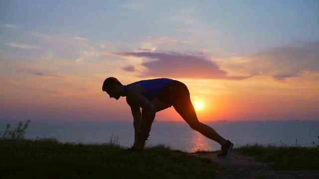 young strong man stretching  downward dog workout outdoor dawn sea slow motion