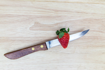 Red strawberry with knife on wooden