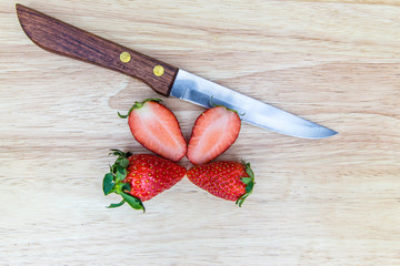Knife with strawberries on wooden