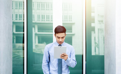 Fototapeta premium Young Asian Businessman working on tablet, Front view, Lifestyle of modern male to communicate, message or use technology in business, Always connected concept