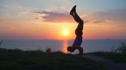 Young strong healthy man show handstand workout outdoor dawn sea slow motion