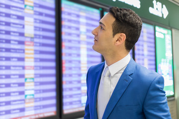 Young businessman ckecking flights schedule in an airport