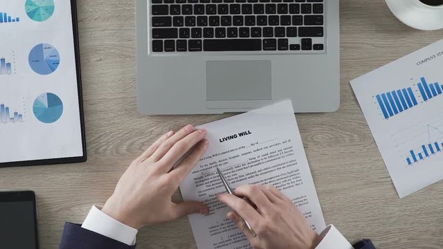 Male proofreading living will before signing, thinking about future, document