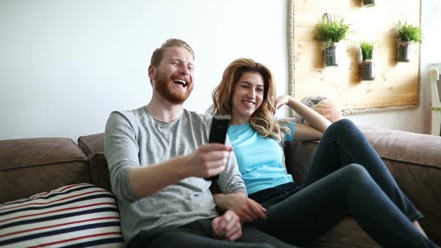 Happy romantic couple smiling having fun and watching tv