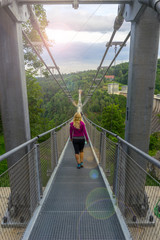 Obraz premium Girl walking over a suspension bridge