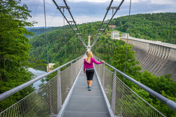 Obraz premium Girl walking over a suspension bridge