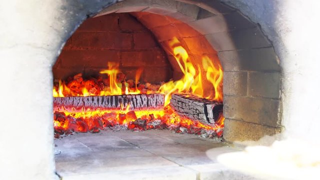 Pizza being baked in traditional wood burning pizza-bread oven in a restaurant. Chef making pizza in commercial kitchen. Pizza Place.