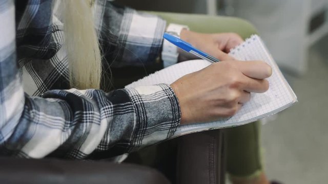 Female hands quickly write text in a notebook. Lesson on eyebrow correction or makeup.