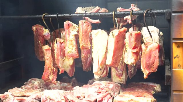 Smoking pork meat, bacon and sausages, food preparation process of cured pork meat delicacy in smokehouse.