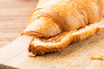 Fresh croissants with salted caramel on a brown wooden background, closeup, horizontal, selective focus
