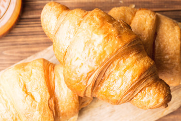 Fresh croissants on a brown wooden background, closeup, horizontal, top view, selective focus
