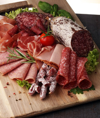 Food tray with delicious salami, pieces of sliced ham, sausage,