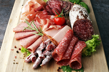 Food tray with delicious salami, pieces of sliced ham, sausage, tomatoes, salad and vegetable - Meat platter with selection