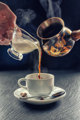 pouring cup of hot coffee and milk with steam
