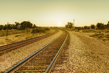 Obraz na płótnie Canvas Vintage Railroad Tracks on Curve Path into the Sun