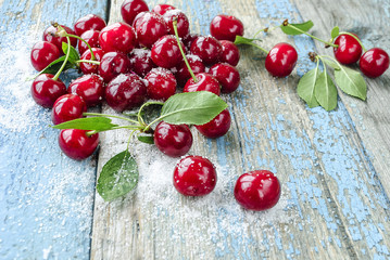 A red ripe juicy cherry is scattered on a wooden surface.
