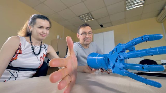 An engineer showing bionic arm movements to a female assistant.