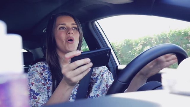Woman texting message with cell phone while driving car doing selfie slow motion