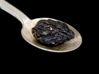 Prune, dried plum, on spoon. HIgh fibre healthy snack.