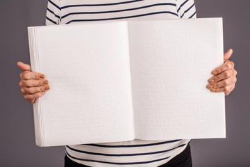 Naklejka premium Hand holding a braille book. Woman show pages.