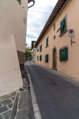 Fototapeta na wymiar Narrow uphill street with walls on both sides in Fiesole, Italy