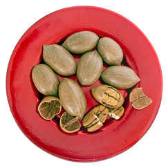 A red plate of pecan nuts. Healthy eating, snack. Isolated on white.