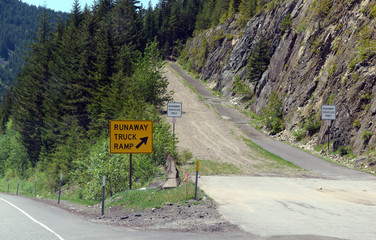 Road sign for Runaway truck ramp in the forest on a mountain road, designed to slow down a vehicle and help prevent accidents if a commercial truck loses braking or loses control down a steep hill. - 160339537