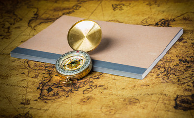 Fototapeta na wymiar Compass and notebook on a vintage map.