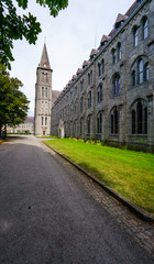 Fototapeta premium Empty driveway leading to building with tall spire tower, Belgium.