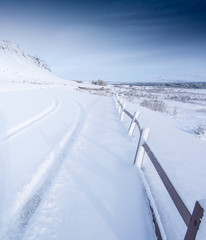 Vertical, deep snow covered road by day with horizon, Iceland, Europe.