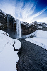 Tourists viewing snow covered landscape and high waterfall, Iceland, Europe.