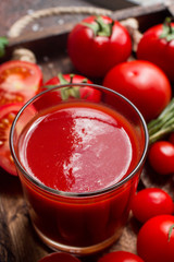 glass of tasty organic tomato juice and fresh tomatoes and herbs on wooden tray in rustic style. Selective focus, healthy lifestyle