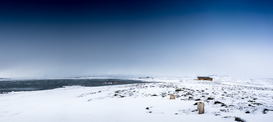 Log cabin in snow covered landscape, in distance, Iceland, Europe.
