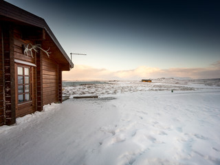 Cosy log cabin in deep snow covered landscape, Iceland, Europe.