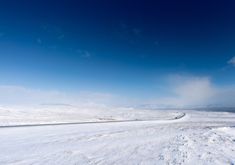 Fototapeta na wymiar Snow covered landscape, distant mountain and blue sky, Iceland, Europe.