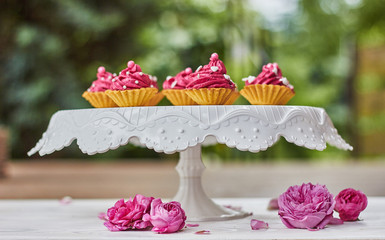 Pink cupcakes decorated with pearls, hearts and roses on the terrace