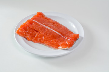 Raw wild king Salmon Fillet lying on white place, against white background