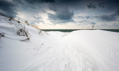Snow covered coastal landscape, with dramatic dark clouds in sky, Ontario, Canada