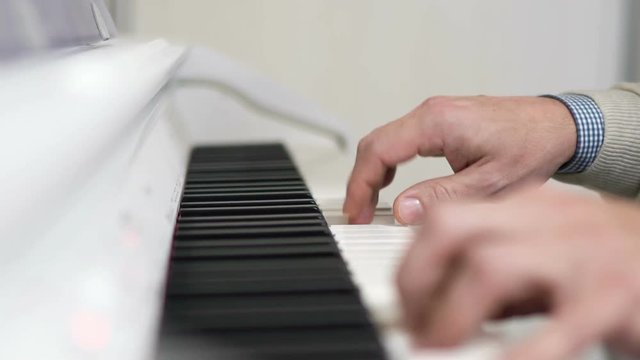 Male hands playing on white piano. Slow motion 120 fps