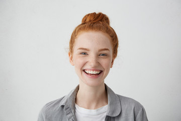 Close-up view of pretty woman with red hair knot, blue charming eyes, freckles and gentle smile having delightful expression after good walk with her boyfriend. Happy female with appealing appearance