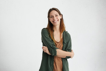 Photo of restful woman with dyed hair standing crossed hands having sincere and delightful smile...