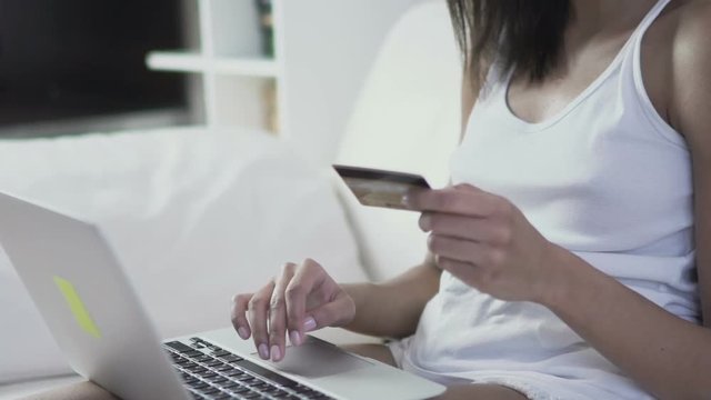Woman holding credit card in hand purchasing online shopping with her laptop. Slow motion 120fps