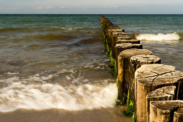 waves breaking at wooden groynes at the baltic sea