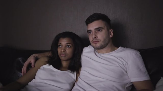 Young couple watching a horror thriller movie at home. 4K