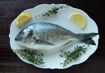Fresh fish with lemon and thyme on a plate