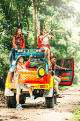 Group of backpacker friend having fun while driving a car to explore forest. Friendship, adventure concept.