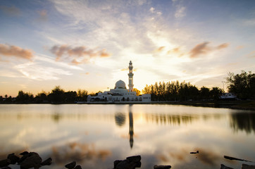 Stunning landscape floating mosque at Terengganu, Malaysia over golden sunset background. reflection and cloudy sky