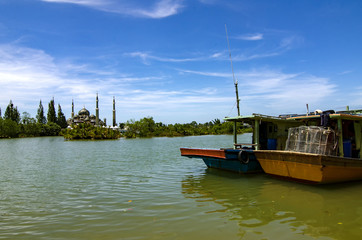 boat anchored near the river bank over crystal mosque and blue sky background at sunny day at Terengganu, Malaysia
