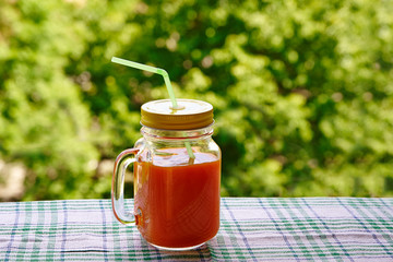 Healthy carrot smoothie in a jar outdoors.